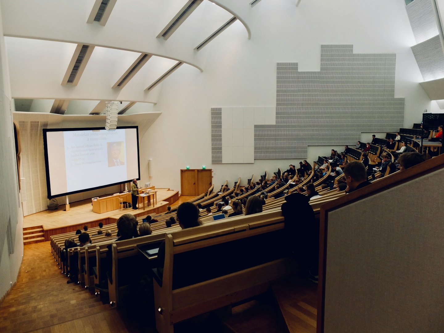 Students attend a presentation in a modern lecture hall.