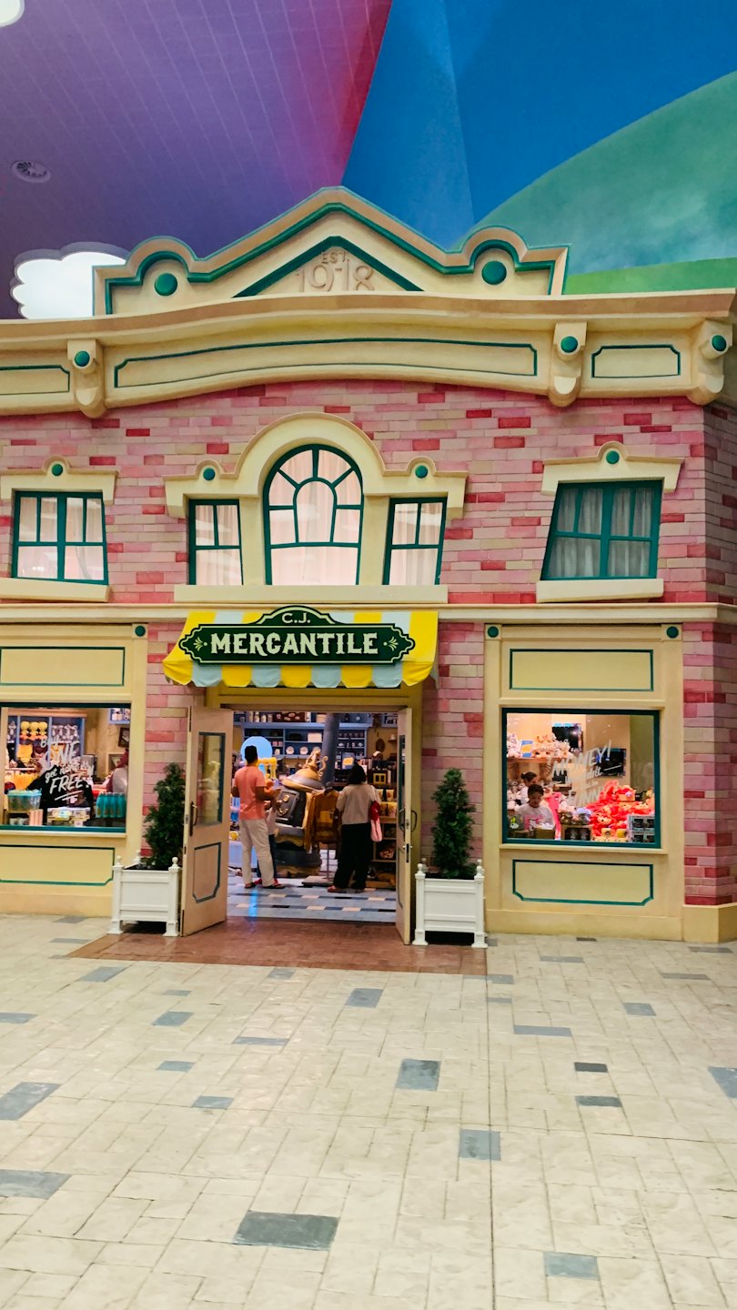 Two customers walk into a colorful mercantile shop storefront.